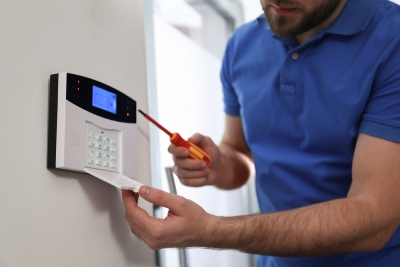 un technicien travaille sur le boitier d'une alarme