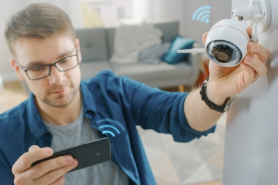 Homme installant une caméra de surveillance dans son domicile.